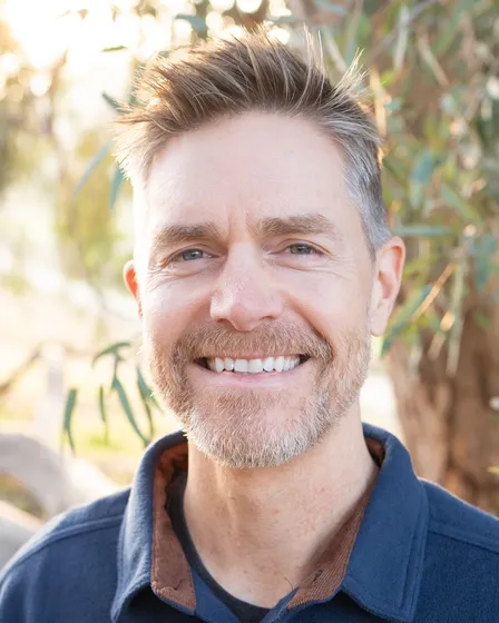Phil Derksen outdoors, smiling, in late-afternoon sun.